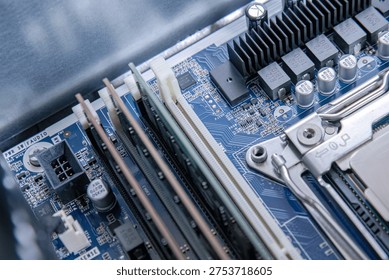 Memory banks aligned beside processor socket on a blue mainboard. Open server interior revealing ram slots and board pathways. Technical hardware view with capacitors, traces, and connectors. Computing platform detail focused on expansion and memory area