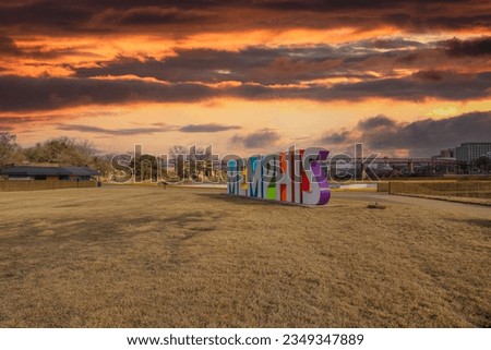 Memphis, Tennessee USA - 11 24 2021: shot of the colorful Memphis sign with skyscrapers and office buildings in the city skyline with yellow grass, blue sky and clouds in Memphis Tennessee USA