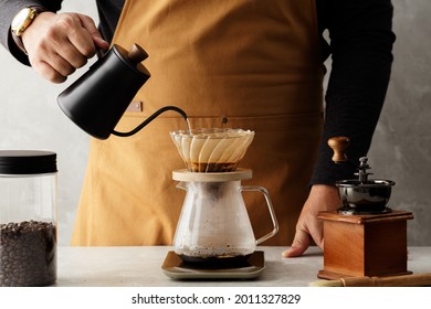 Men barista making a drip coffee, pouring hot water from kettle over a ground coffee powder - Shutterstock ID 2011327829
