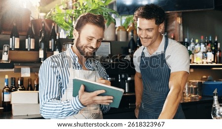 Men, bartender and happy with tablet, talking and sales report at pub, results and revenue at diner. People, mentor and digital touchscreen with app for inventory, menu and excited at restaurant