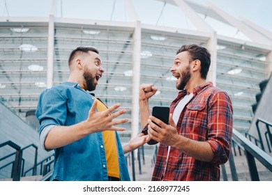 Men being happy winning a bet in online sport gambling application with football stadium on the background.  - Shutterstock ID 2168977245