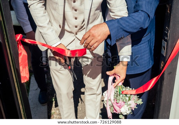 men in business suits and ties cut the red\
ribbon with scissors