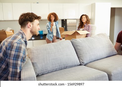 Men Carrying Sofa Helping With Move Into New Home