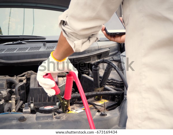 Men Charge Car Battery\
and use phone