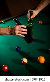 Men clinking beer bottles above snooker table full of balls.?