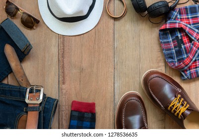 Men clothing set  with brown shoes , bracelet, blue jeans , leather belt, white hat, socks, red shirt, sunglasses and earphone on wooden background, Top view - Shutterstock ID 1278536635