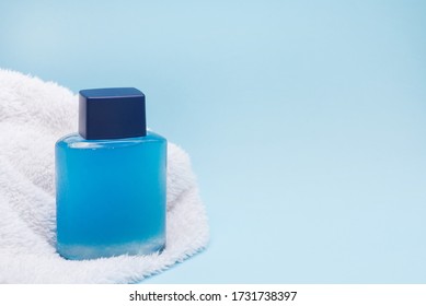 Men cosmetic product aftershave and white towel on blue background with copy space