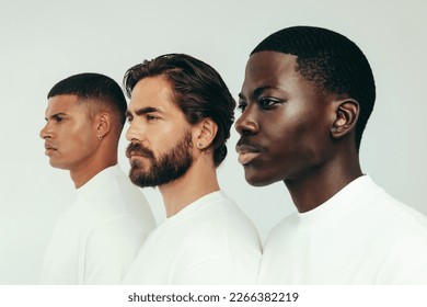 Men displaying confidence and beauty as they stand together in a studio. Three young men, each with a unique skin tone, show the flawless results of self-care and a consistent skincare routine.