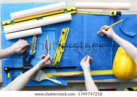 Men draftsmans on table draw construction project. An architect builds project on paper using measuring instruments. Builders calculate risks building. Joint work design department and builder