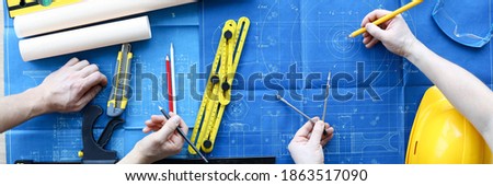 Men draftsmans on table draw construction project. An architect builds project on paper using measuring instruments. Builders calculate risks building. Joint work design department and builder