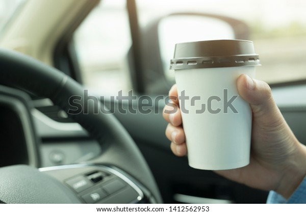 Men are\
eating coffee from a cup of coffee in the\
car