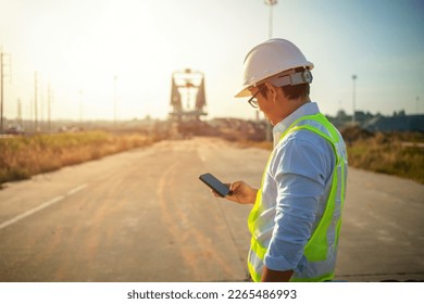 men engineer working on site at wind turbine farmMen Engineer using mobile phone and holding tablet for inspecting and working at construction site - Powered by Shutterstock