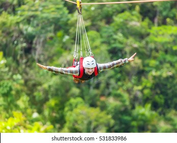 Men Enjoying Zip-line Flying Over The Forest