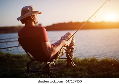 Men Fishing In Sunset And Relaxing While Enjoying Hobby