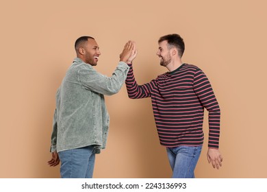 Men giving high five on beige background - Powered by Shutterstock