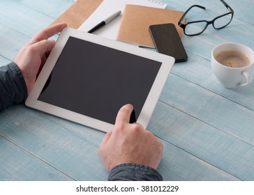 Men Hand Clicks A Blank Screen Tablet Computer, Closeup On A Light Wooden Table. Concept Man Working In The Morning From Home Using Tablet Computer Or Working Outside The Office