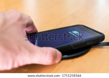 Men hand putting smartphone on wireless battery charge. New technology that allow to recharge mobile phone without wire charger or inductive charging.