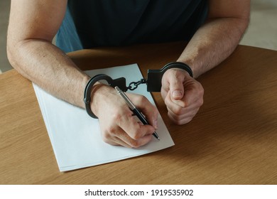 Men hands with handcuffs fill the police record, confession. on top of the police investigative detective. Arrest, bail, criminal, prison. fingerprints, criminal