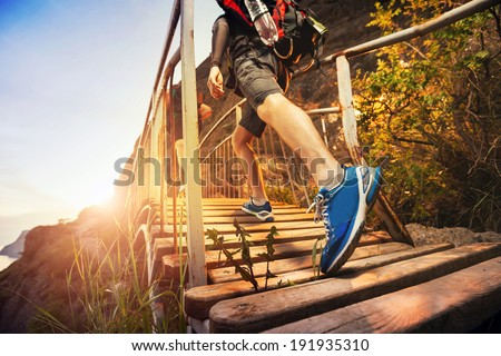 Men are hiking in the mountains, walking on a wooden bridge at sunset. Healthy lifestyle.