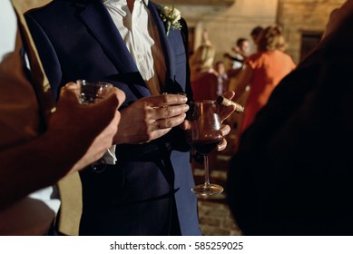 Men Hold Glasses With Wine And Smoke Cigars Standing Outside