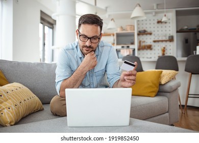 Men Holding Credit Card And Using Laptop At Home Office. Young Adult Male Making Online Purchase. Online Shopping. Young Handsome Man Shopping Online With Credit Card And Laptop At Home