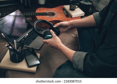 Men Holding Headphone For Wearing  And Listening Music On Sofa At Home To Check Melody From Music Creator. Relax Home Concept.