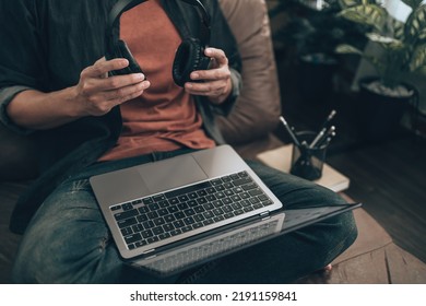 Men Holding Headphone For Wearing  And Listening Music On Sofa At Home To Check Melody From Music Creator. Relax Home Concept.