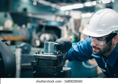 Men Industrial Engineer Wearing A White Helmet While Standing In A Heavy Industrial Factory Behind. The Maintenance Looking Of Working At Industrial Machinery And Check Security Setup In Factory.