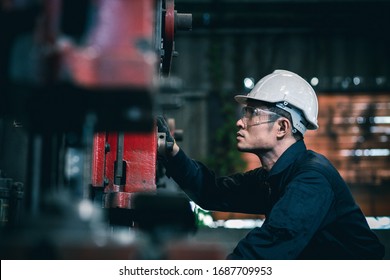 Men Industrial Engineer Wearing A White Helmet While Standing In A Heavy Industrial Factory Behind. The Maintenance Looking Of Working At Industrial Machinery And Check Security System Setup In Fact