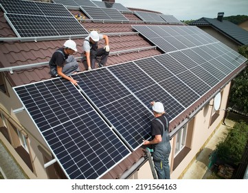Men installers mounting photovoltaic solar moduls on roof of house. Engineers in helmets installing solar panel system outdoors. Concept of alternative and renewable energy. Aerial view. - Shutterstock ID 2191564163