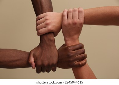 Men joining hands together on beige background, closeup - Shutterstock ID 2245944615