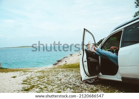 men legs stick out from car parked at sea beach. summer vacation