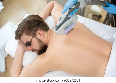 Men Lying At Beautician's During Laser Back Hair Removal Therapy