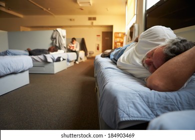 Men Lying On Beds In Homeless Shelter