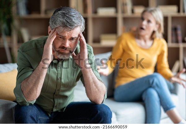 Men Midlife Crisis. Stressed Middle Aged Male\
Sitting Upset After Quarrel With Wife, Pensive Mature Man Touching\
Head In Despair, Suffering Depression And Relationship Crisis,\
Selective Focus