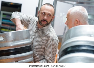 Men Moving Metal Barrels In A Brewery