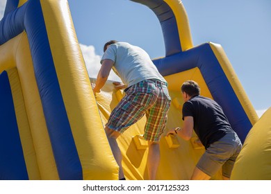 Men on an inflatable ride. Obstacle lane to run. Entertainment in the park. Summer active rest. Inflatable design. Playground for adults. - Powered by Shutterstock