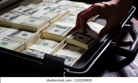 Men packing 100 US dollar bills in to briefcase