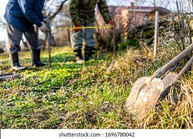 Men People With Measuring Tape Working On Vegetable Winter Garden For Post Raised Bed Cold Frame In Ukraine Dacha And Closeup Of Shovel Spade