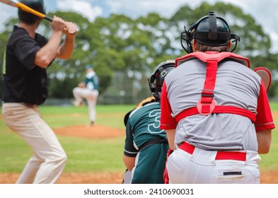 Men playing baseball game. Batter getting ready to hit a pitch during ballgame on a baseball diamond, field.