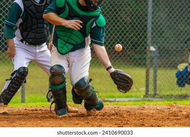 Men playing baseball game. Catcher is trying to catch a baseball during ballgame on a baseball diamond, field. - Powered by Shutterstock