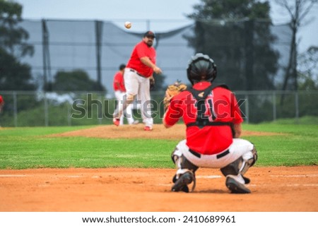 Men playing baseball game. Catcher is getting read to catch baseball during ballgame on a baseball diamond, field.