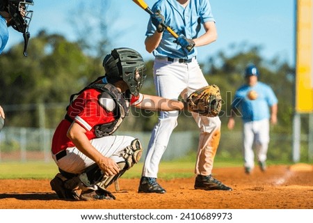Men playing baseball game. Catcher is trying to catch a baseball during ballgame on a baseball diamond, field.