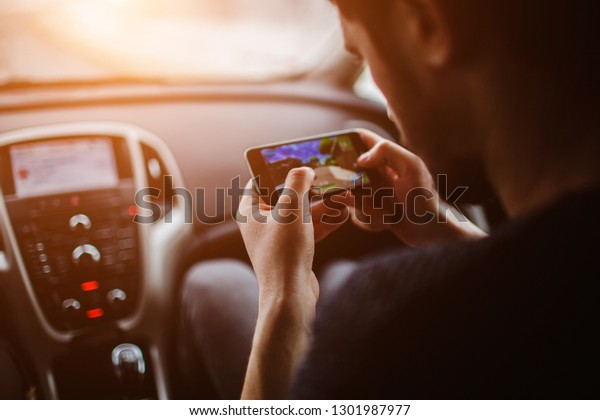 Men are playing on the phone. On the background of
the car.