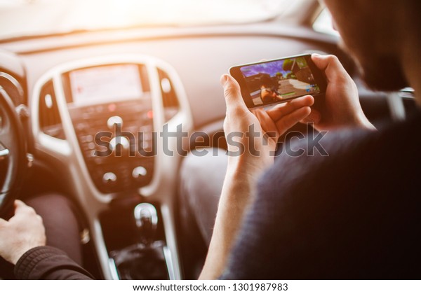 Men are playing on the phone. On the background of\
the car.