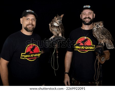 Men posing in photoshoot with owl on black isolated background