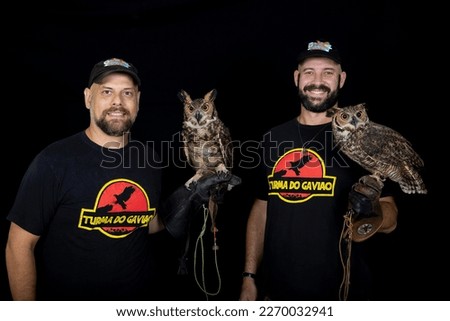 Men posing in photoshoot with owl on black isolated background