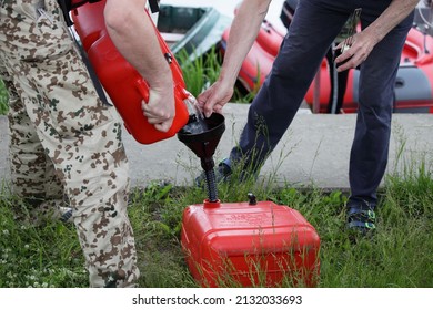 Men Pour Gasoline From A Red Plastic Fuel Tank On Inflatable Motorboat Background. Refueling For Trip On A Motor Boat.