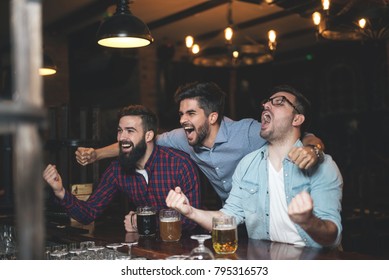 Männer in der Kneipe schauen Fußballspiel und trinken Bier.