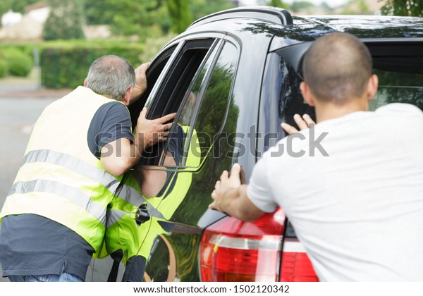 men pushing a car during\
break down